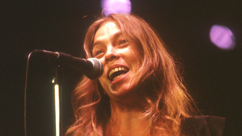 Rickie Lee Jones souriant et chantant sur scène dans les années 1970