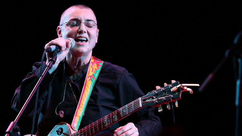 Sinead O'Connor jouant de la guitare avec des lunettes