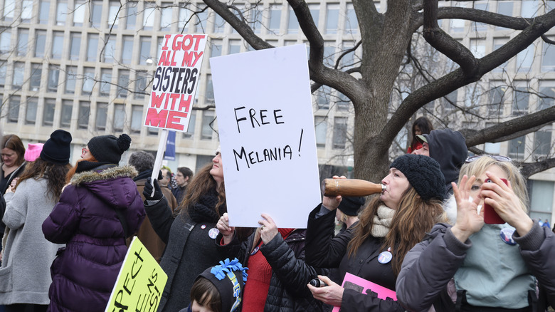 Femmes tenant une pancarte avec l'inscription 'Libérez Melania' lors d'une manifestation