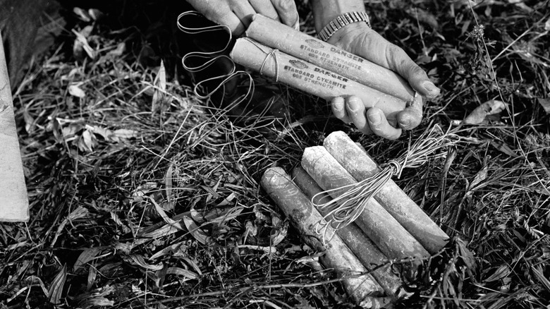 Ancienne photographie d'un homme manipulant des bâtons de dynamite