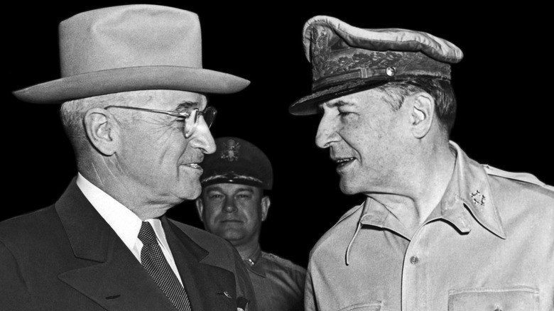 Harry Truman et Douglas MacArthur discutant avec un homme en arrière-plan