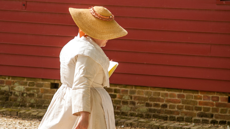 Femme vêtue de costumes de l'époque coloniale se promenant à Colonial Williamsburg, Virginie.