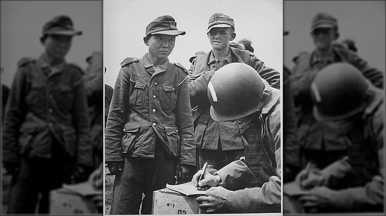 Soldat japonais portant un uniforme allemand, s'adressant aux soldats américains après sa capture lors du D-Day en Normandie.