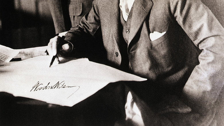 Woodrow Wilson examinant un document avec un stylo à la main.