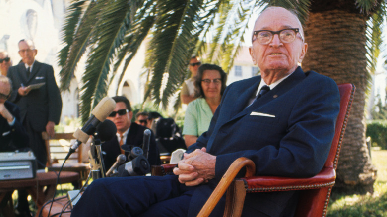 Harry S. Truman seated outside with reporters