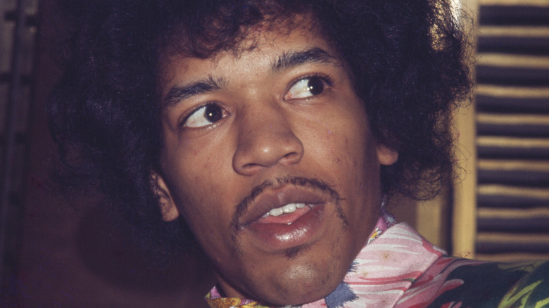 Jimi Hendrix regardant sur sa gauche dans une chemise à fleurs