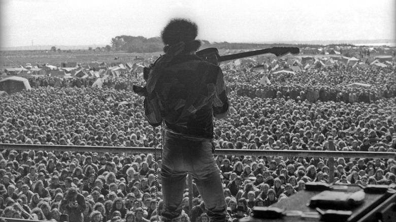 Jimi Hendrix de dos, jouant devant un large public