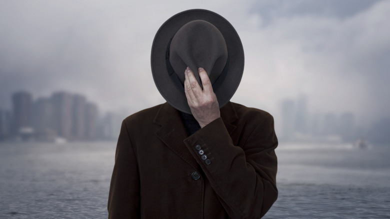 Spy covering face with hat