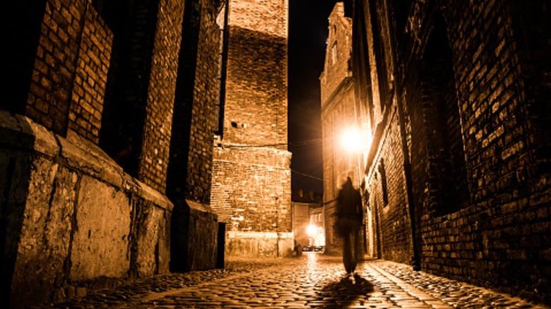 Silhouette floue marchant dans une rue pavée la nuit