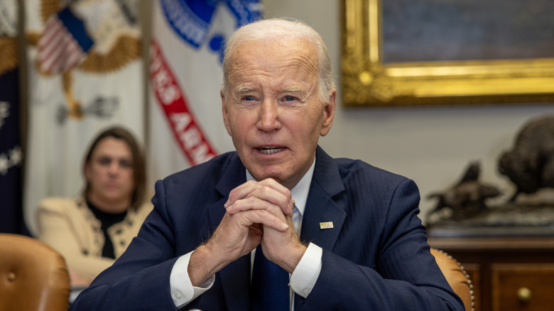 Joe Biden assis, parlant, les mains entrelacées