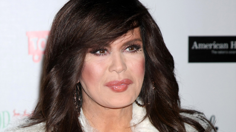 Marie Osmond avec des lèvres pincées dans un manteau en fourrure blanche