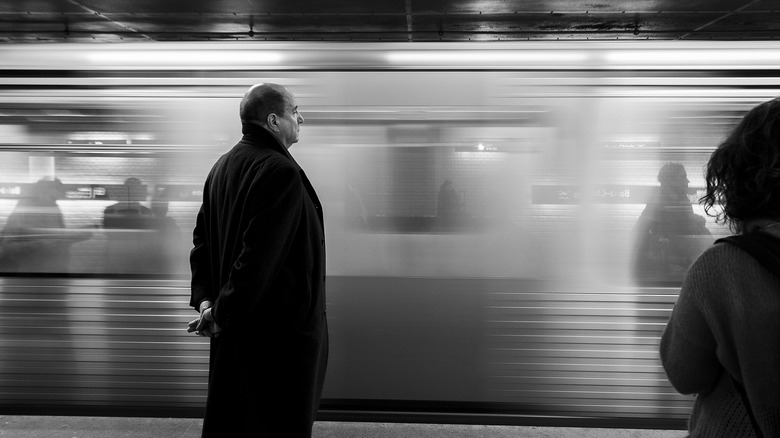 Homme chauve en costume noir sur un quai de métro