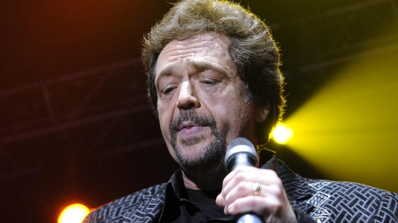 Jay Osmond sur scène, regardant vers le bas tout en tenant un microphone