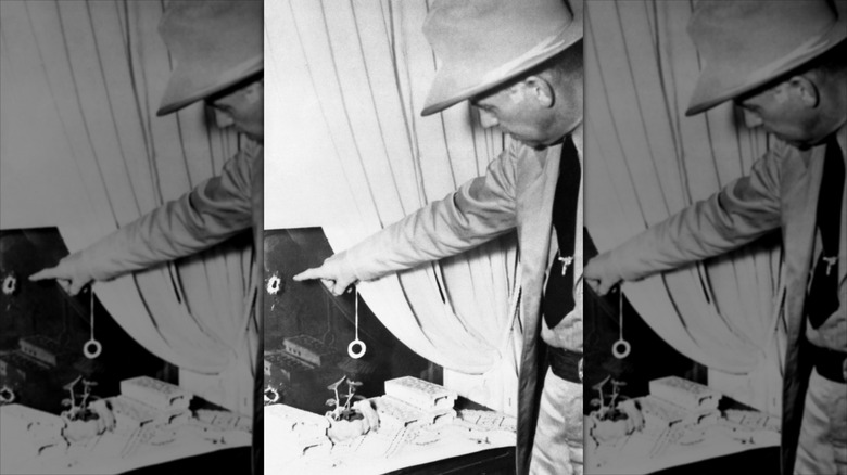 Captain M.T. Gonzaullas of the Texas Rangers points out holes in the window of the Starks home after shooting.