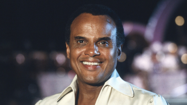 Un jeune Harry Belafonte souriant avec des lumières en arrière-plan