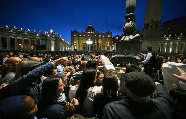 Des dizaines de personnes tendent les bras pour recevoir des exemplaires d’une édition spéciale du journal du Vatican, L’Osservatore Romano, annonçant la mort du pape François, sur la place Saint-Pierre.