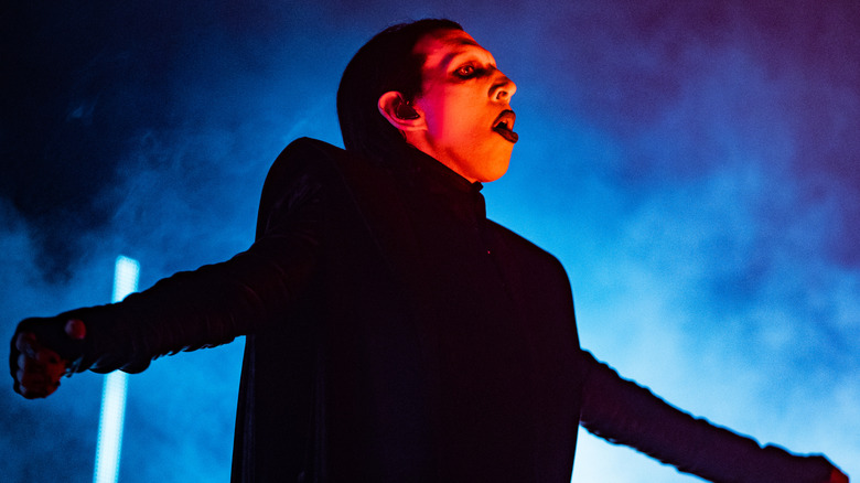 Marilyn Manson sur scène illuminée en bleu dans un costume noir